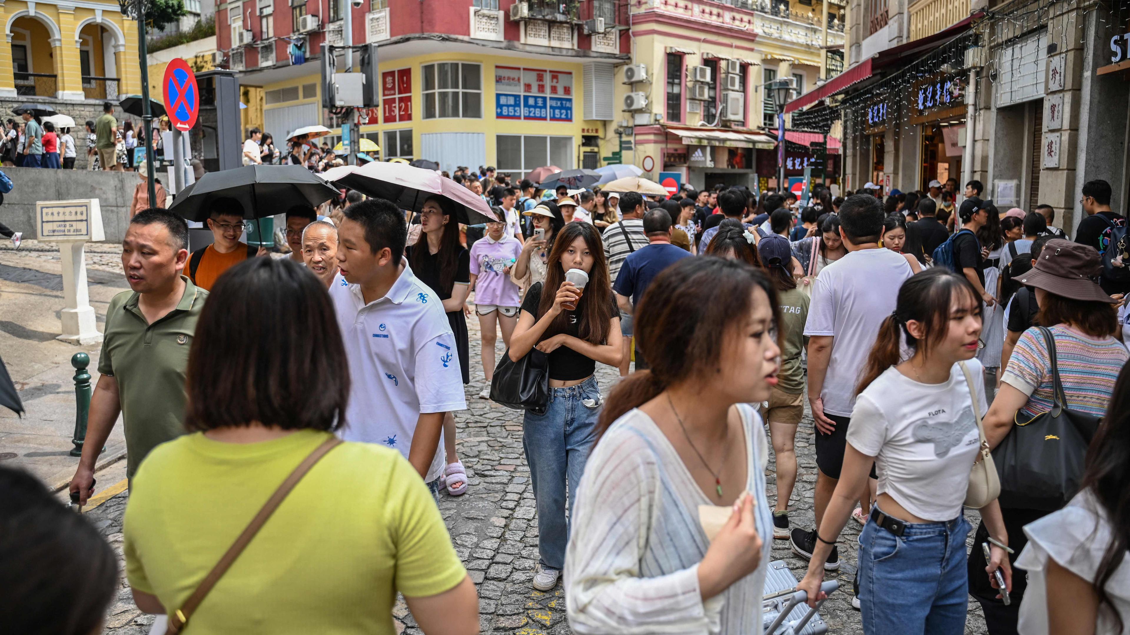 This photo taken on October 3, 2023 shows Chinese tourists visiting Macau during the country�s week-long holiday at the start of October. Macau's baccarat and poker tables were teeming once again as millions of Chinese tourists marked "Golden Week" in October, with post-pandemic travel surging despite the country's economic slowdown. (Photo by Peter PARKS / AFP) / To go with AFP story Macau-China-economy-gambling, FOCUS by Holmes CHAN