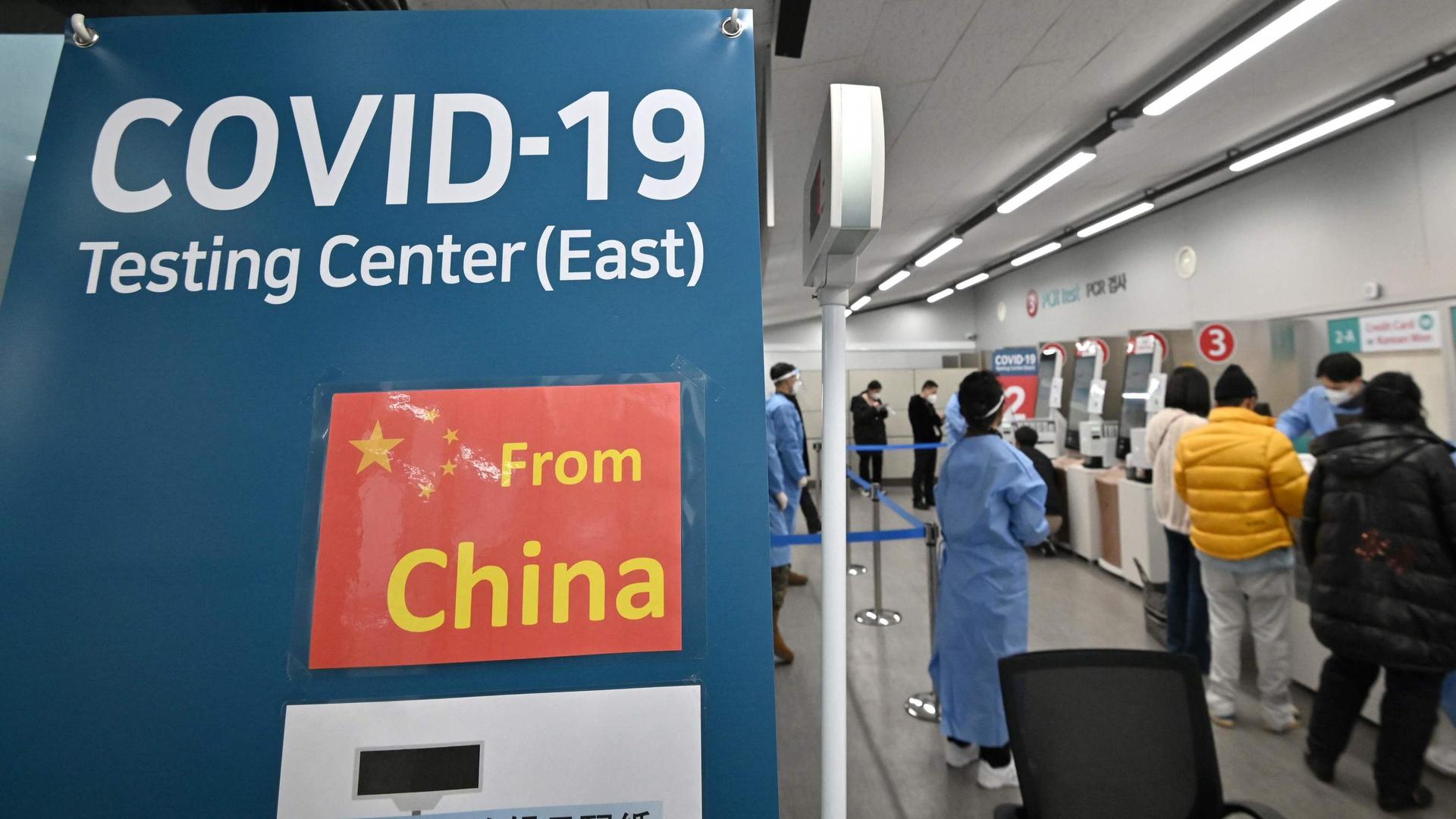Trabalhadores da saúde guiam os viajantes que chegam da China num centro de testes covid-19 no Aeroporto Internacional de Incheon, na Coreia do Sul. 