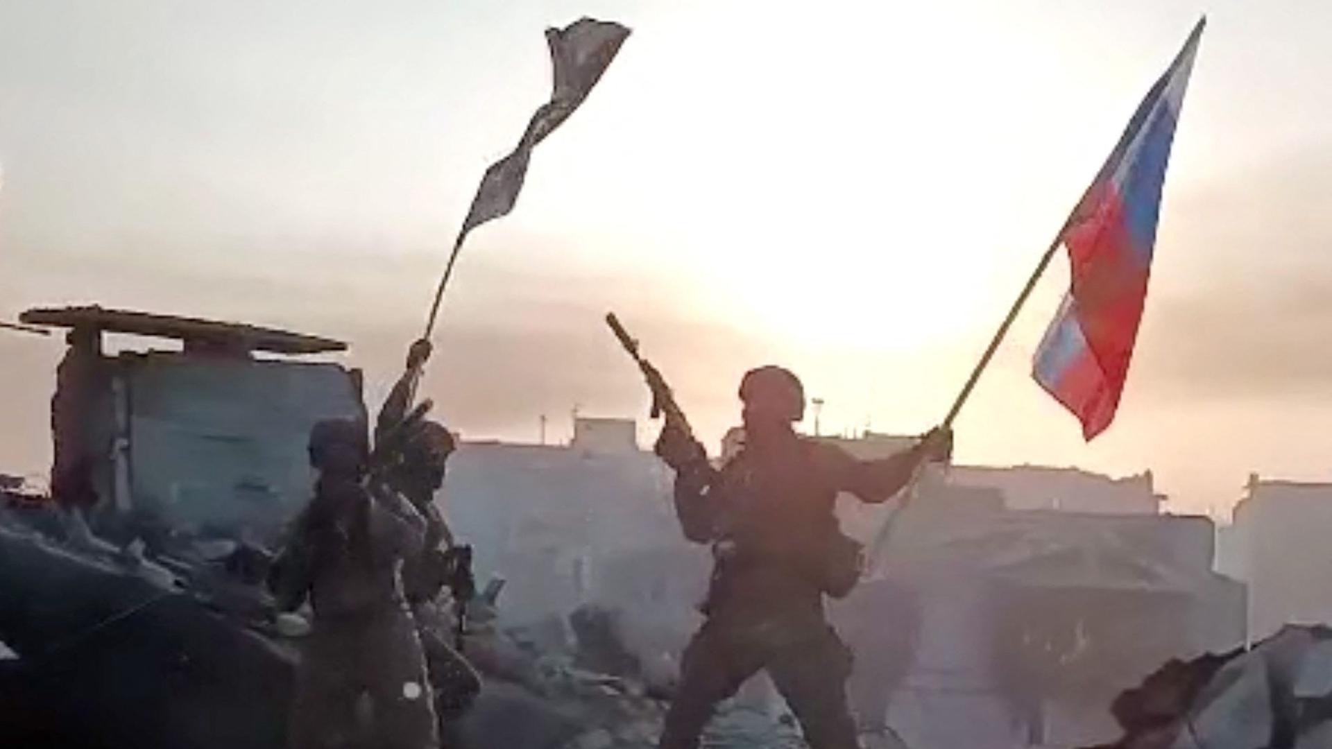 This video grab taken from a handout footage posted on May 20, 2023 on the Telegram account of the press service of Concord -- a company linked to the chief of Russian mercenary group Wagner, Yevgeny Prigozhin -- shows members of Wagner group waving a Russian national flag and Wagner Group's flag on the rooftop of a damaged building in Bakhmut, amid the Russian invasion of Ukraine. Russia's private army Wagner claimed on May 20, 2023, the total control of the east Ukrainian city of Bakhmut, the epicentre of fighting, as Kyiv said the battle was continuing but admitted the situation was "critical". Bakhmut, a salt mining town that once had a population of 70,000 people, has been the scene of the longest and bloodiest battle in Moscow's more than year-long Ukraine offensive. The fall to Russia of Bakhmut, where both Moscow and Kyiv are believed to have suffered huge losses, would have high symbolic value. (Photo by Handout / various sources / AFP) / RESTRICTED TO EDITORIAL USE - MANDATORY CREDIT "AFP PHOTO /  Telegram channel of Concord group" - NO MARKETING - NO ADVERTISING CAMPAIGNS - DISTRIBUTED AS A SERVICE TO CLIENTS