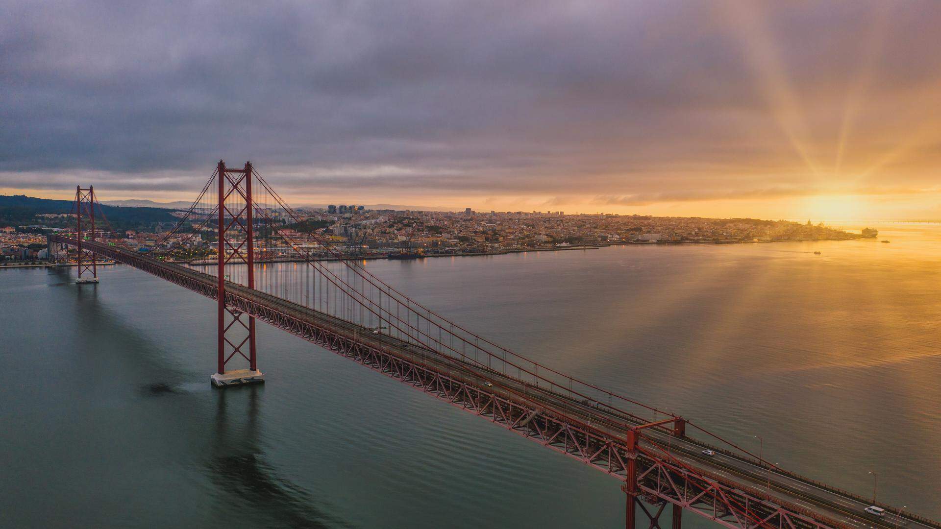 An aerial view shot of a suspension bridge in Portugal during a beautiful sunset, Lisbon, Lisboa