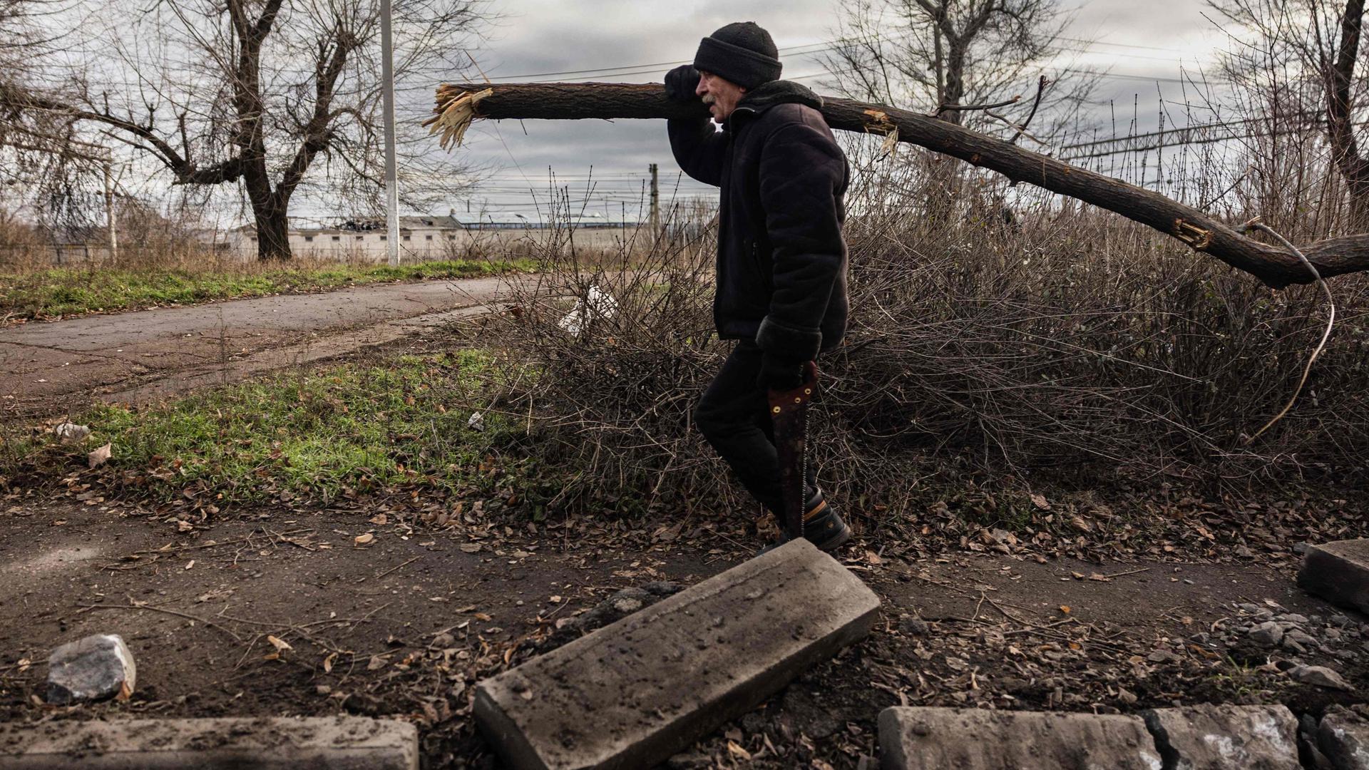 Um civil apanha lenha para se aquecer e cozinhar na cidade do leste da Ucrânia, a 22 de dezembro 