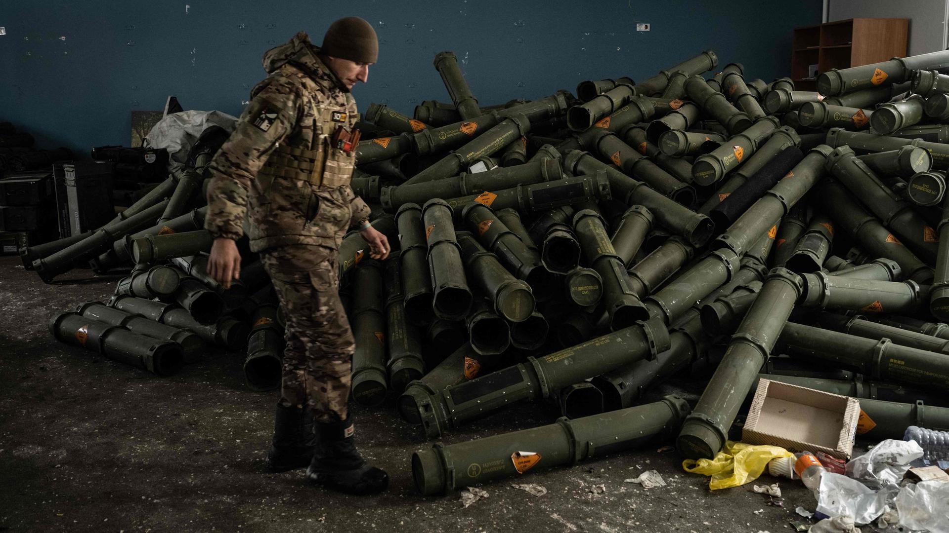 Um soldado ucraniano perto de uma pilha de cartuchos de munições vazios em Bakhmut, a 15 de fevereiro de 2023.