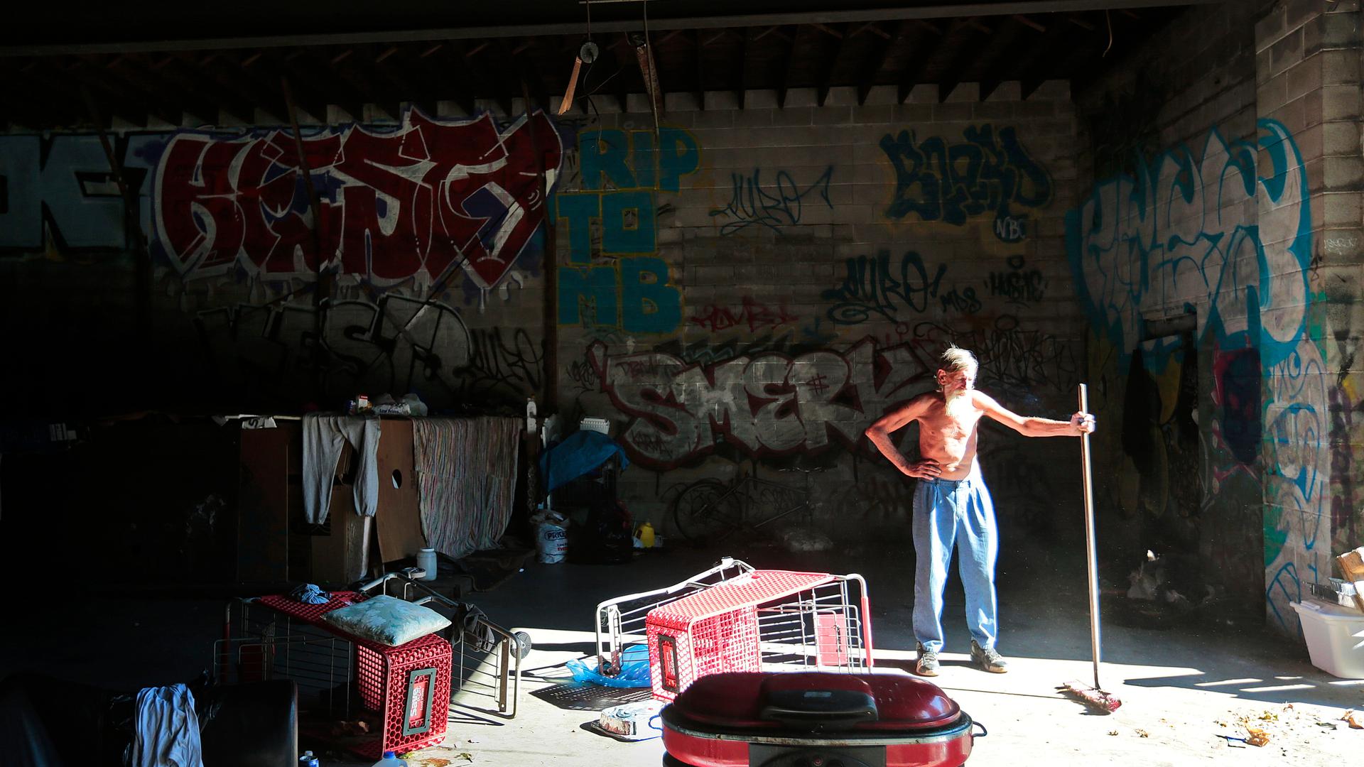 Um cidadão sem-abrigo limpa a garagem onde costuma passar as noites.