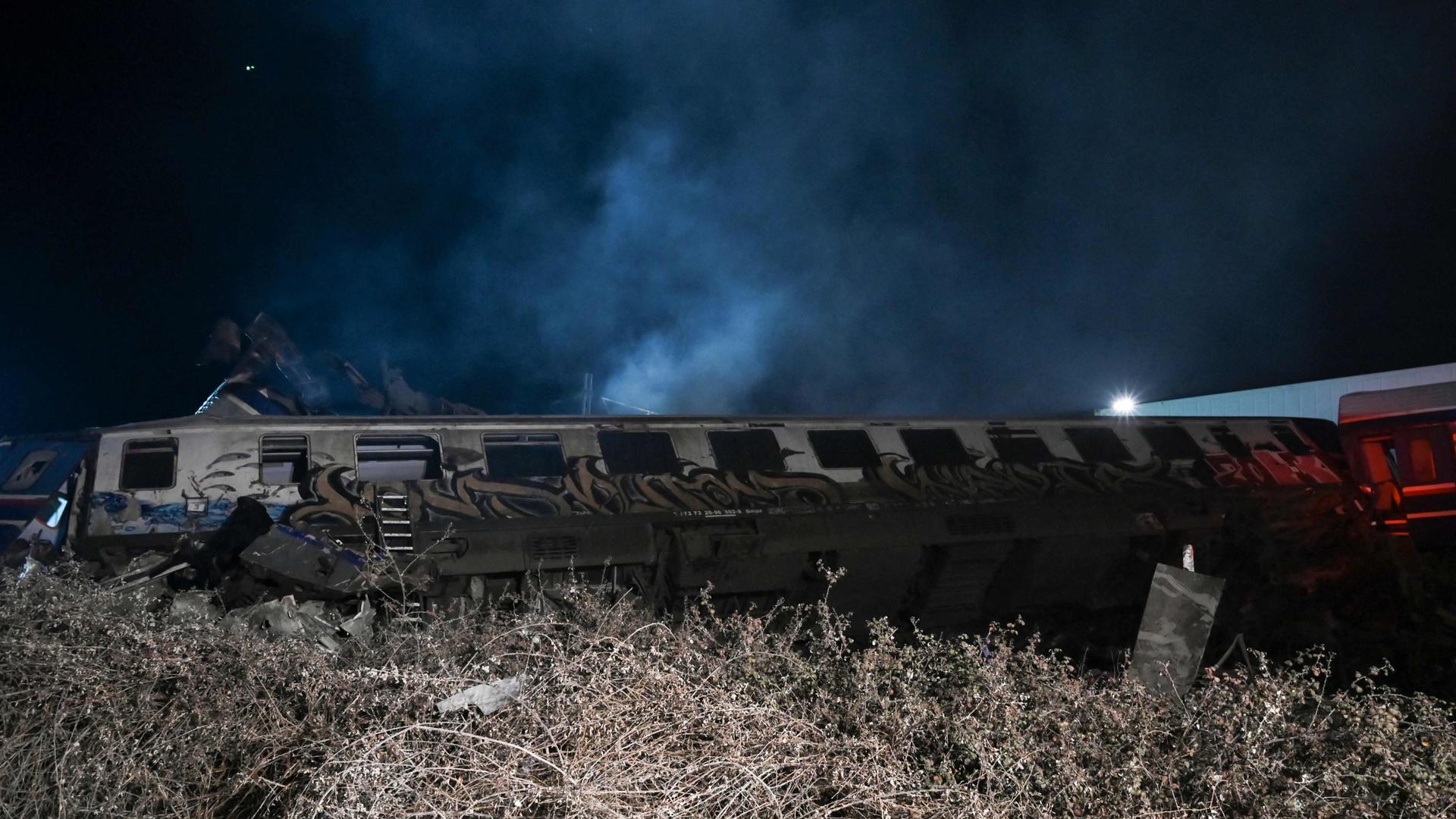 TOPSHOT - Derailed cars are lying on their sides after a train accident in the Valley of Tempi near Larisa, Greece on March 1, 2023. - At least 29 people were killed and another 85 injured after a collision between two trains caused a derailment near the Greek city of Larissa late Tuesday night, February 28, 2023, authorities said.
A fire services spokesman confirmed that three carriages skipped the tracks just before midnight after the trains -- one for freight and the other carrying 350 passengers �- collided about halfway along the route between Athens and Thessaloniki. (Photo by Sakis MITROLIDIS / AFP)