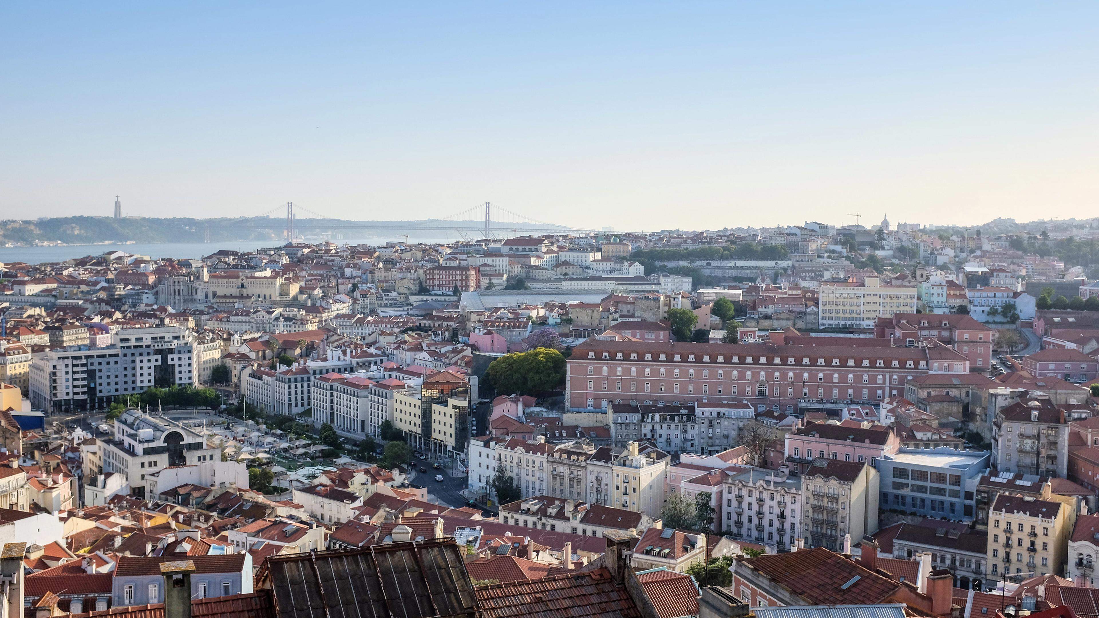 An aerial photo of Lisbon covered in buildings with the sea on the background in Portugal