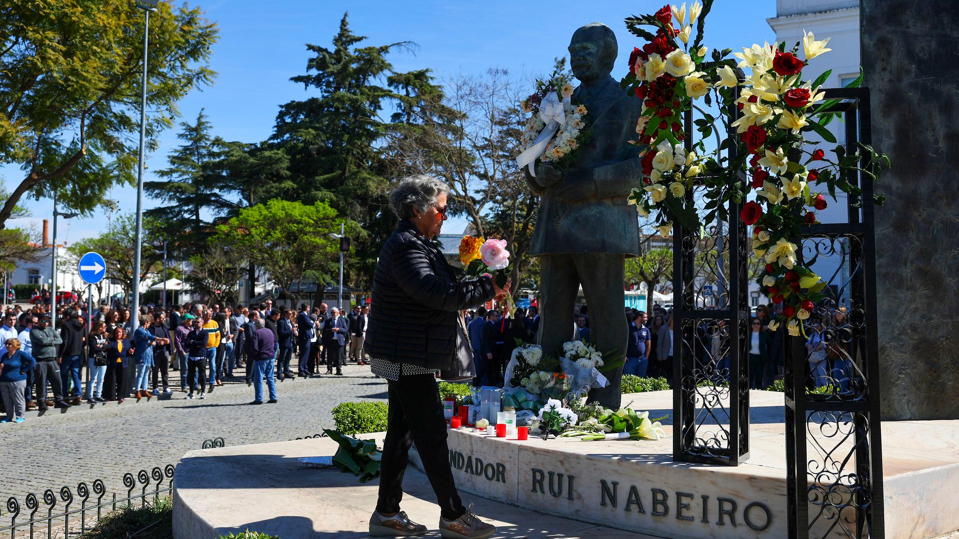 Uma mulher coloca as tradicionais flores de papel, junto à estátua do empresário Rui Nabeiro, momentos antes da passagem cortejo fúnebre, na rotunda de entrada em Campo Maior.