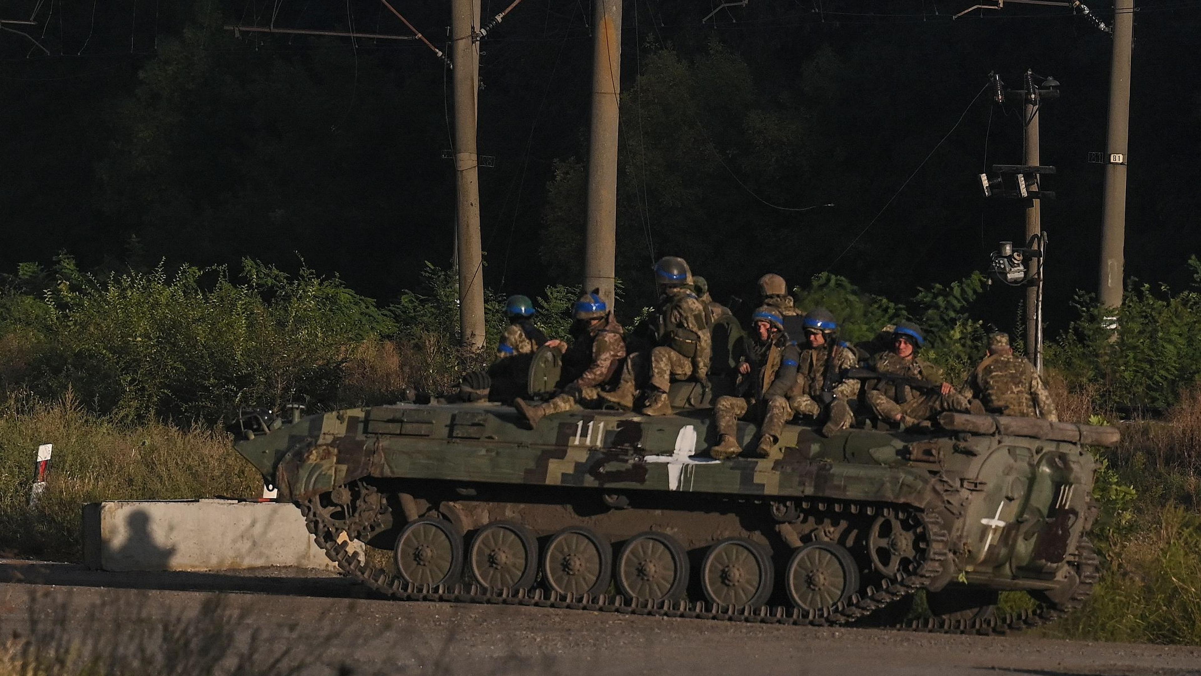 Soldados do exército ucraniano sentados no topo de um veículo armado em Kkharkiv.