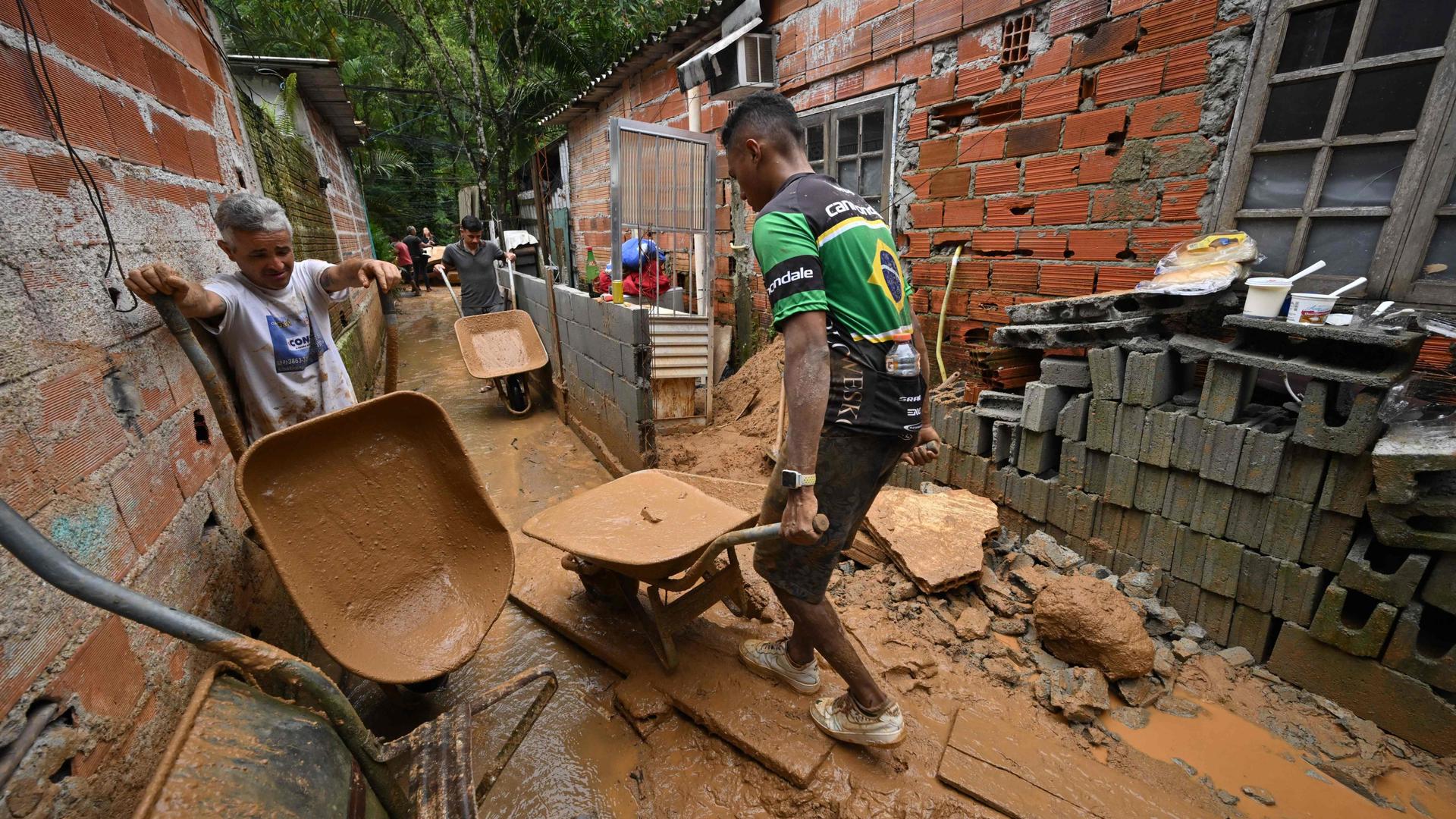 People remove mud from a flooded house after torrential rain caused flooding and landslides at the Juquehy district in Sao Sebastiao, Sao Paulo state, Brazil, on February 20, 2023. - Flooding and landslides triggered by torrential rain in Brazil claimed at least 36 lives on Carnival weekend in southeast Sao Paulo state, authorities said Sunday. (Photo by NELSON ALMEIDA / AFP)