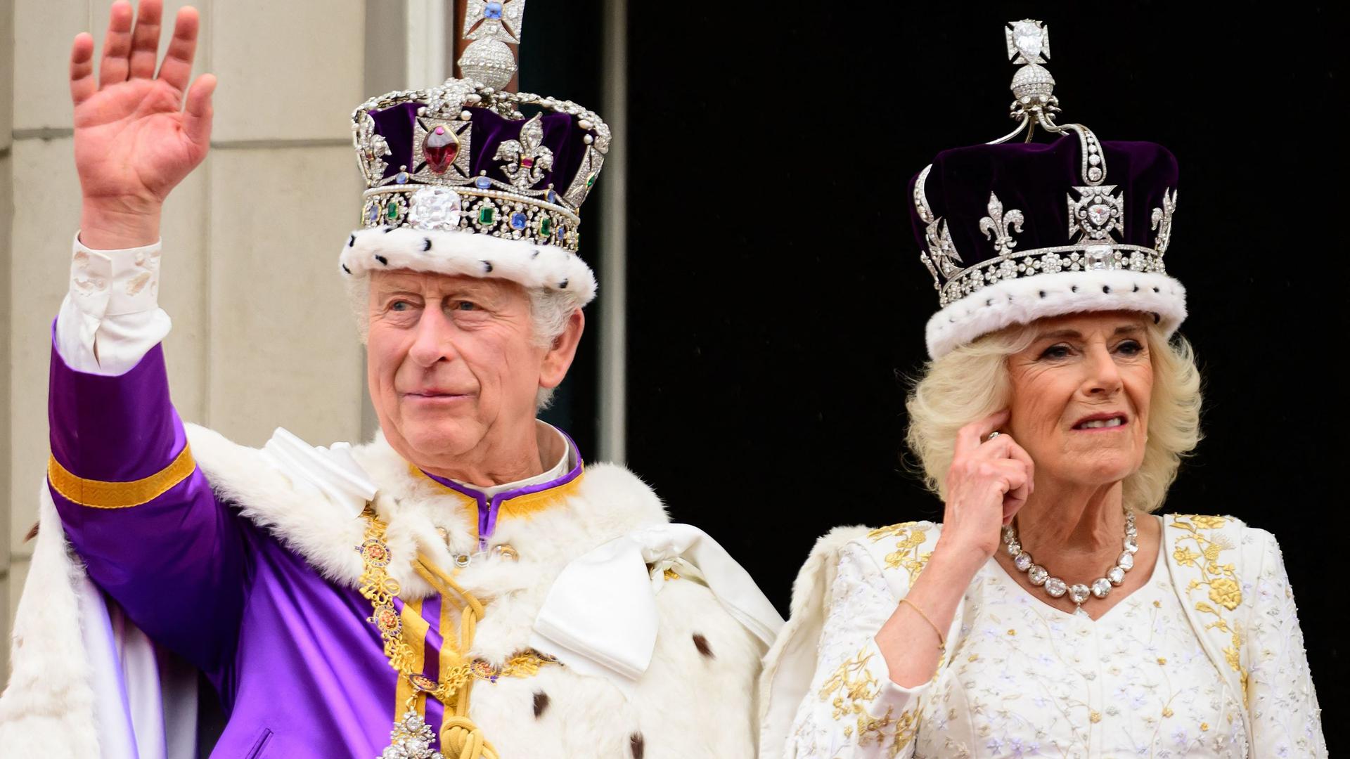 Os reis Carlos III e Camilla acenam aos populares.