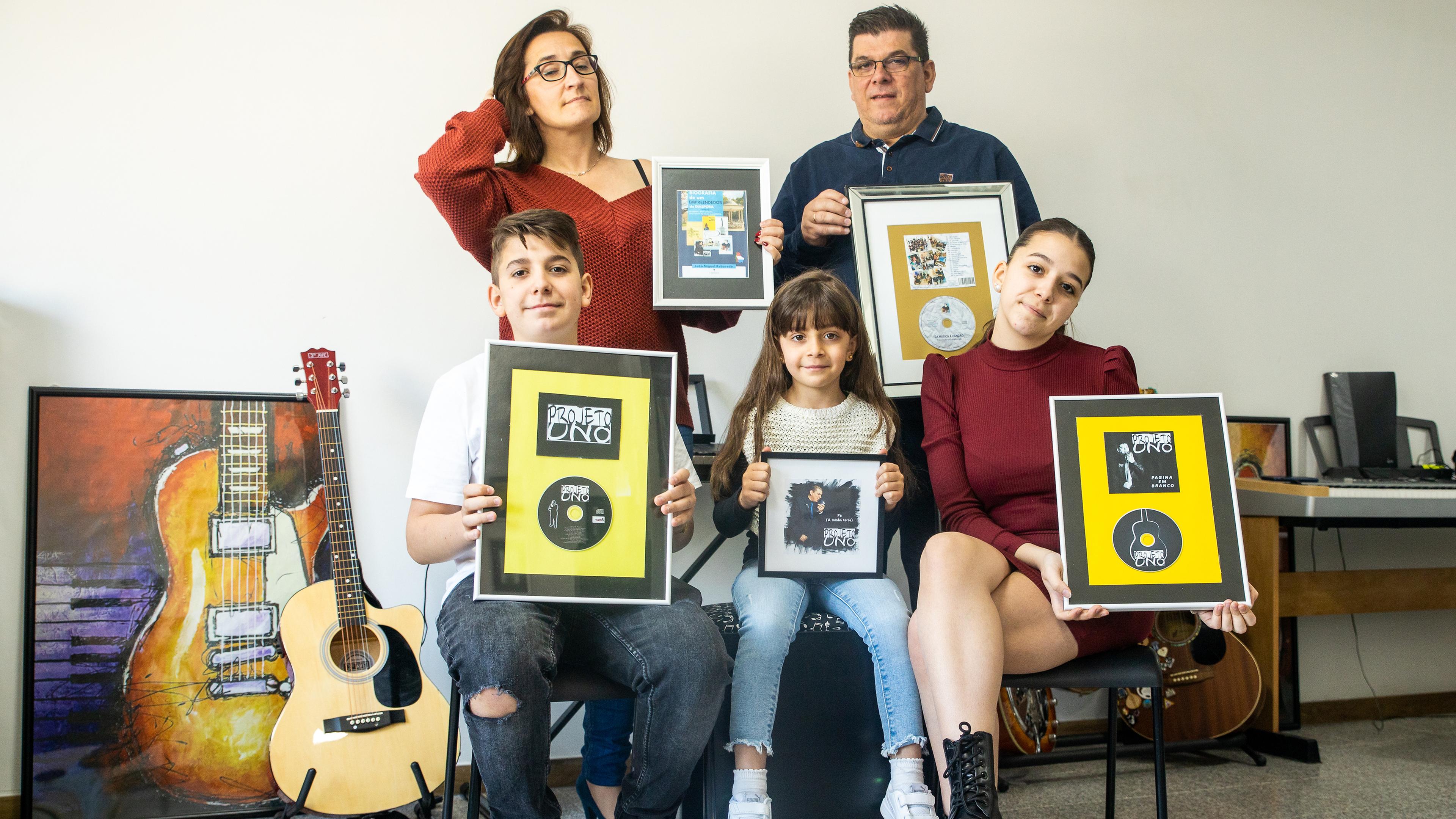 O casal João e Anabela Reboredo com os três filhos, Iuri, Iara e Lara, com as capas dos discos e livros que o pai tem editado no Luxemburgo.