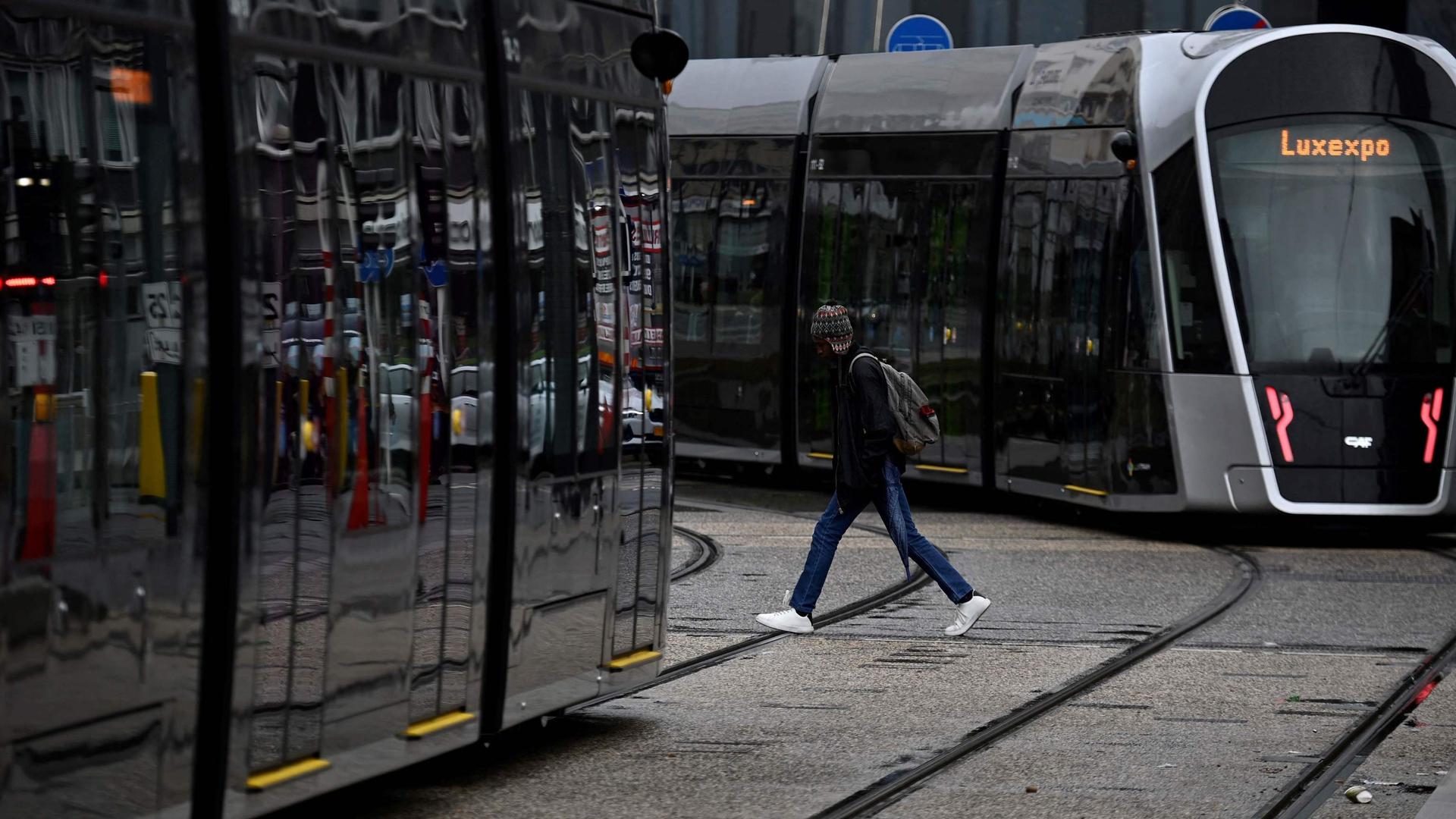 Um homem atravessa a plataforma do tram em frente da Estação Central do Luxemburgo.
