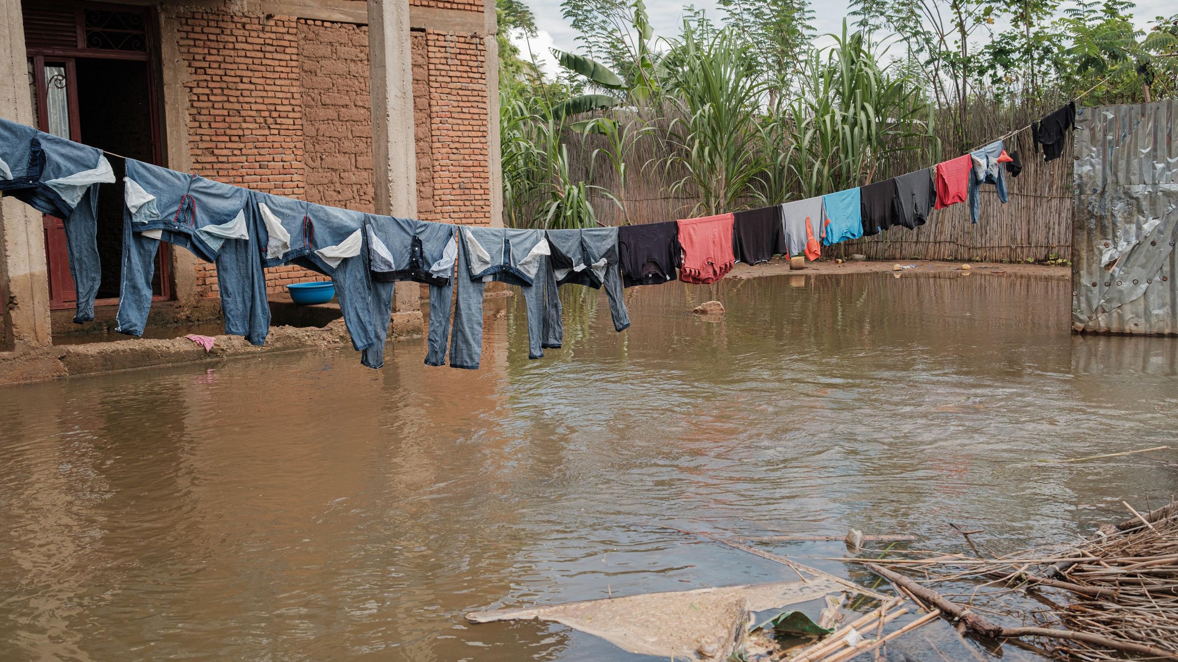 TOPSHOT - Clothes are seen while hanging to dry in an area of houses covered on water following flash floods in the Gatumba district of Bujumbura, on April 19, 2024. The government of Burundi and the United Nations have launched an appeal for financial aid to cope with the "devastating effects" of months of relentless rainfall that has displaced nearly 100,000 people. East Africa has been experiencing torrential rains in recent weeks that have cost the lives of at least 58 people in Tanzania in the first half of April, and 13 people in Kenya. (Photo by Tchandrou Nitanga / AFP)